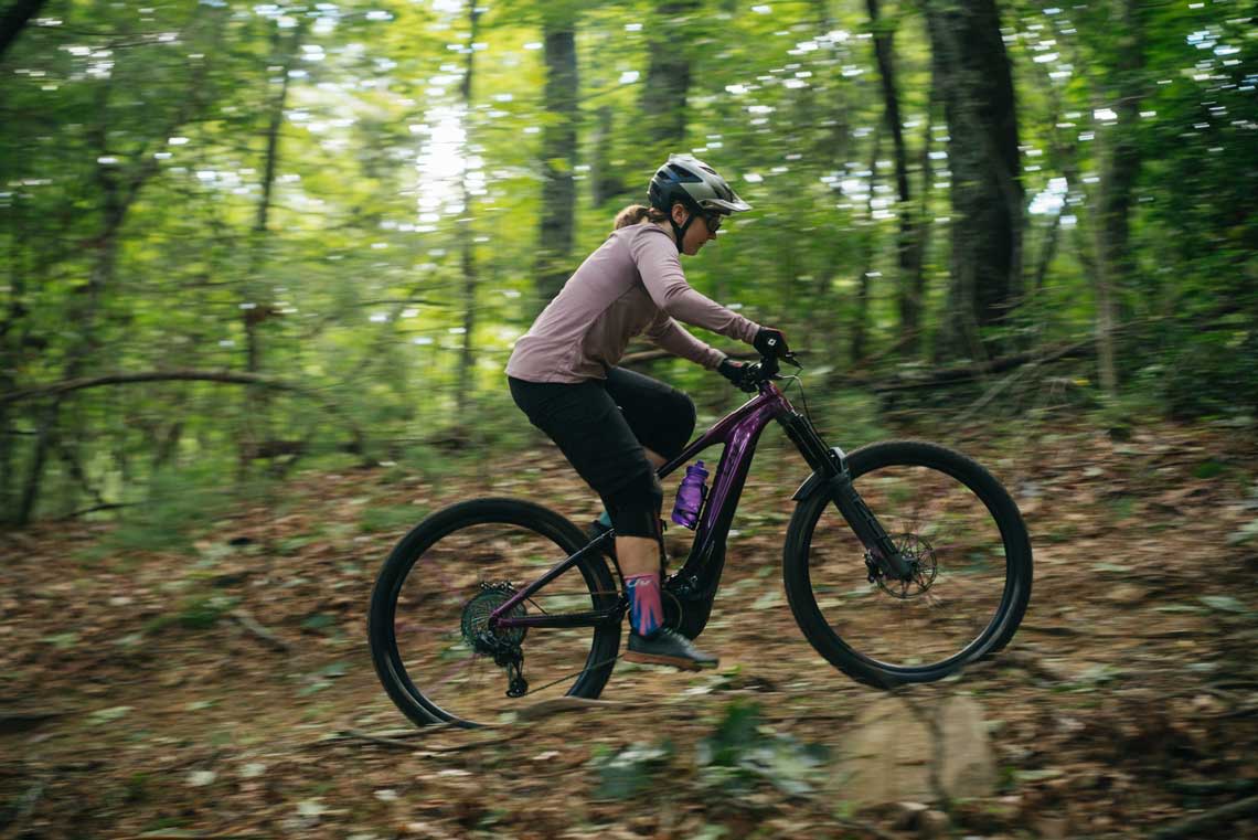 a woman climbing on an e-mtb with her chest up