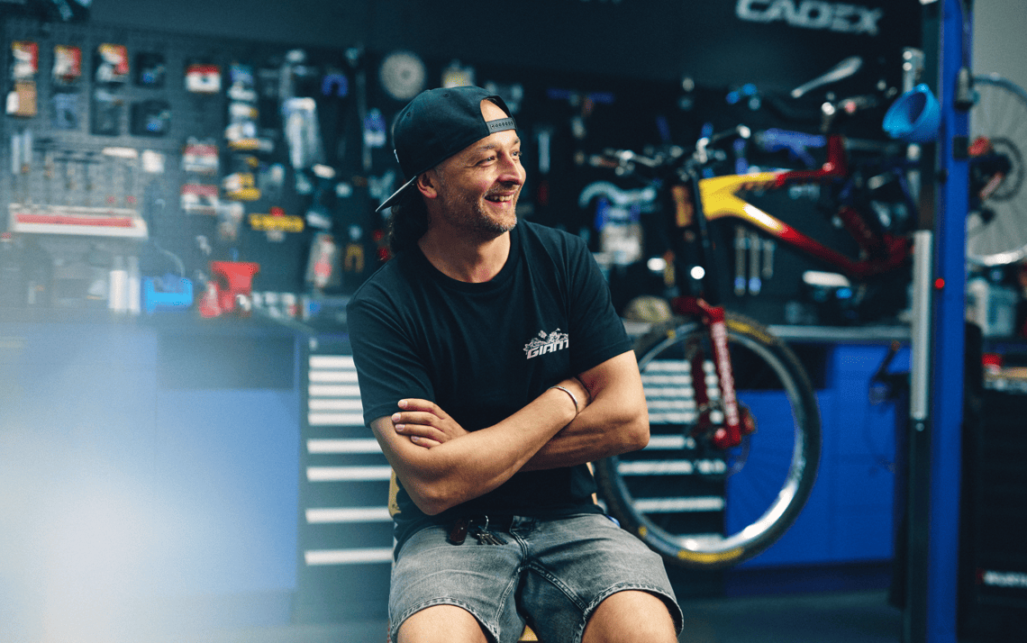 Head of Service at Giant Store Düsseldorf smiling in front of the bike service area.