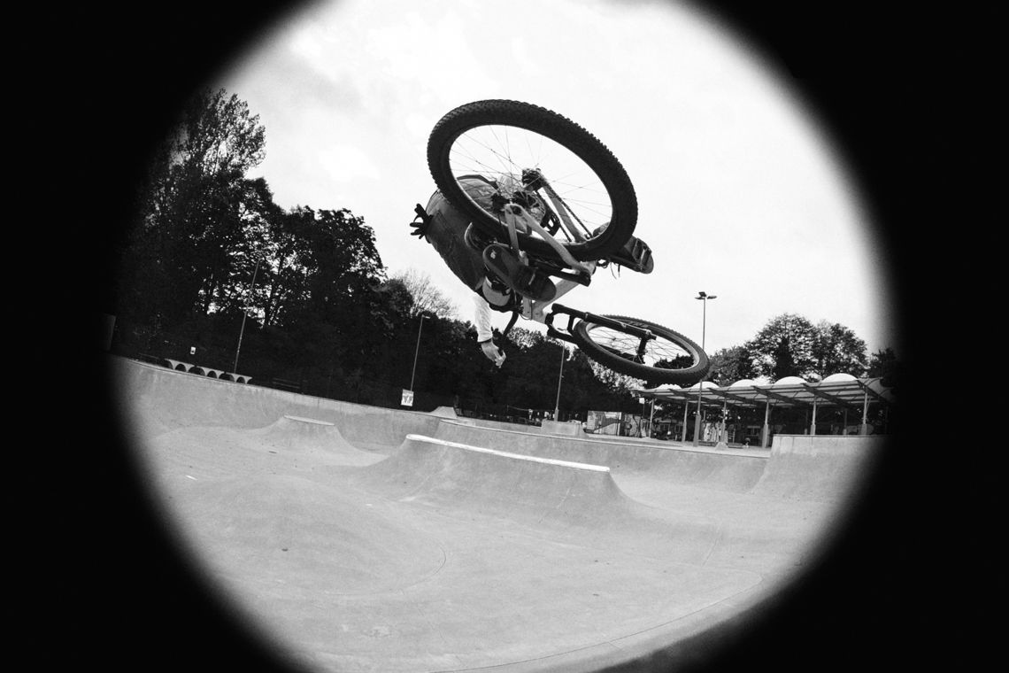 Giant retail staff performing a bike trick at a skate park.