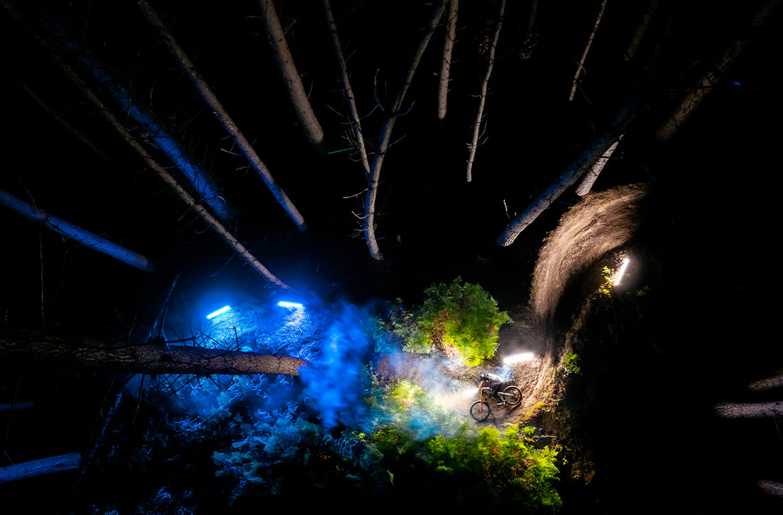 Mountain bike athlete Sascha Kim riding through a glowing forest.