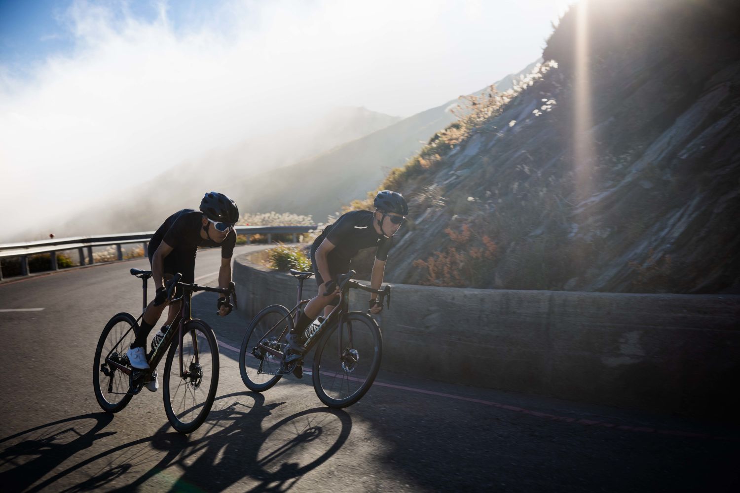 Two road cyclists ascend through a hairpin corner on Giant TCR Advanced SL 0.