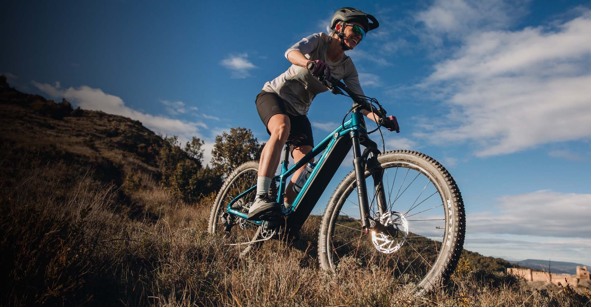 A woman rides the Lurra E+ down a grassy hill