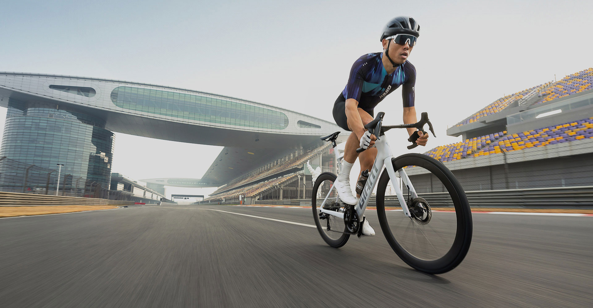 Road cyclist riding aero road bike on race track