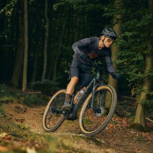 A mountain biker charges down a forest trail on a Giant Talon E+ hardtail.