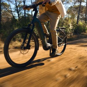 Close up of a cyclist riding Giant Anytour X E+ through a forested dirt road.