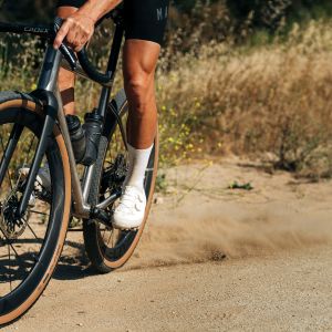 A gravel cyclist skids his rear CADEX GXR gravel tire creating a cloud of dust.
