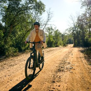 Cyclist approaches riding Giant Anytour X E+ on dirt road.