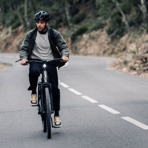 A cyclist approaches on a bike path riding their Giant AnyTour E+ electric city bike.