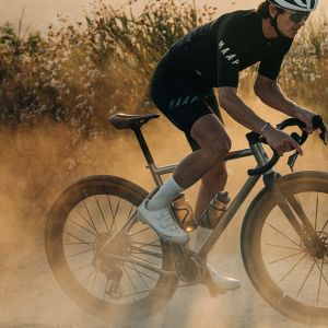 A cyclist on a gravel bike rides a remote mountain road with CADEX MAX GXR wheels.