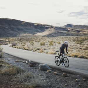 Cyclist riding through valley road on CADEX Max 40 wheels.