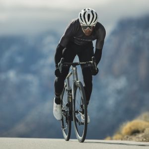 Road cyclist approaches out of the saddle on road bike with CADEX Aero integrated handlebars.