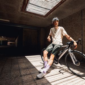 A cyclist sits on the top tube of their Giant Contend SL road bike while waiting for friends in the shade.