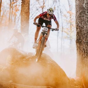 A XC mountain biker charges over a medium sized drop on her Liv Pique Advanced Sl.