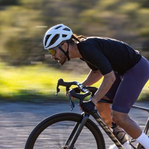 A side view of a cyclist wearing a Giant Rev Pro Helmet while sprinting in the drops of his Giant Propel.