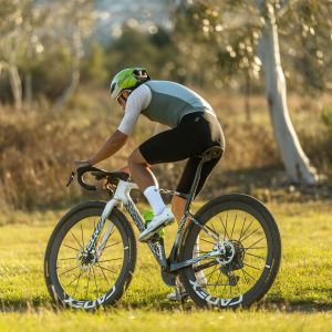 A gravel cyclist on a Giant revolt Advanced SL speeds past wearing Giant Charge Pro gravel/XC shoes.