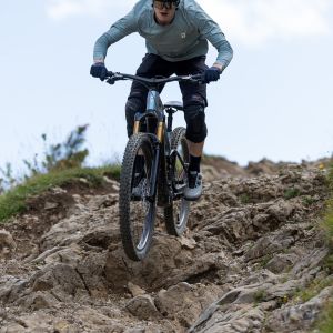 A mountain biker descends a rocky technical line on a mountain trail riding a Giant Trance Advanced E+ with Giant TRX HD E-Mtb wheels.