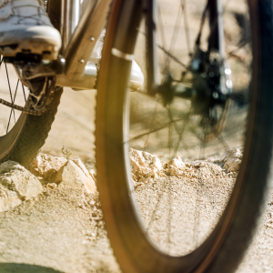 A close up look at the CADEX Max GXR wheels on a gravel cyclists bike as they ride over a rocky portion of fire road.