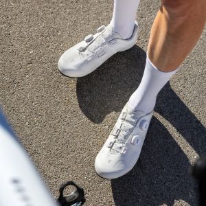 An overhead look at a cyclist's Giant Surge road shoes as they stand next to their bike.