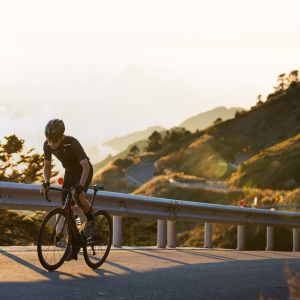 Cyclist ascending mountain road at sunset on Giant TCR Advanced SL.
