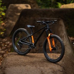 A Giant STP 24 kids dirt jumper staged on an angle in the woods.