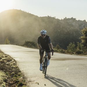 Road cyclist approaches on Giant Advanced Pro 0 with sunny mountain backdrop.