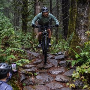 A woman riding the new Embolden mountain bike down a rocky section of trail