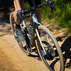 A gravel cyclist rides by on a Giant Revolt Advanced wearing Giant Charge gravel shoes.