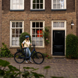 A woman stands in front of her house with her Giant Entour E+ city bike.