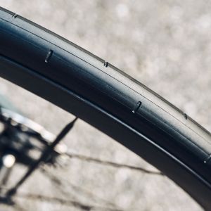 A close up overhead look at the tread on a black side-walled CADEX Aero Tire motionless on a road.