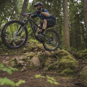 Rider launches Trance 29 off a small forest tech feature.