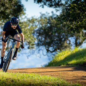 A cyclist wearing Giant Charge gravel shoes sprints down an oak tree lined dirt road.