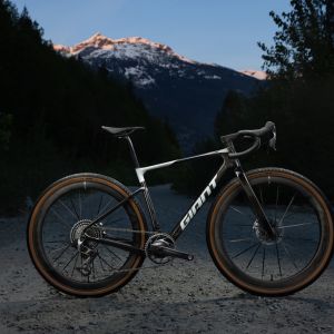 The Giant Revolt Advanced SL 0 staged on a dirt road with snow capped mountains in the background.