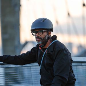 A cyclist wearing a Giant Novo Mips city helmet stops and takes a look at the city view as the sun starts to set on a bridge.