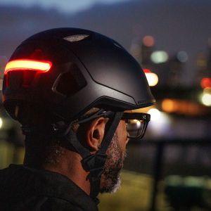 Rear view of a cyclist wearing a Giant Novo Mips helmet with the rear safety light activated at dusk.
