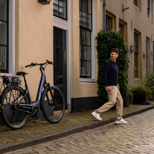A man walks by a Giant Entour E+ city bike leaning up against a wall.