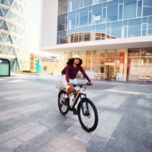 A female cyclist rides through the city on her Liv Tempt E+ EX hardtail.