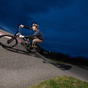 A close up look as a rider comes over a roller into a berm at a concrete bike park riding a Giant STP 26.