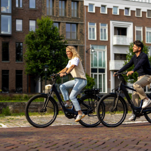 A man and woman on Giant Entour E+ city bikes ride down a cobbled road.