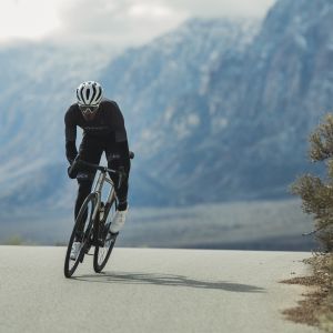 Road cyclist riding out of the saddle with mountain backdrop.