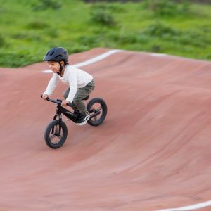 Child riding Giant Pre rCarbon coasts down a roller at a pump track.