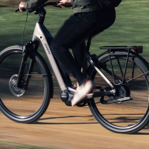 A side view of a cyclist riding their Giant AnyTour E+ city bike on a dirt road.