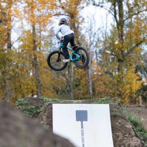 A young rider catches big air off a jump at a bike park on a Giant STP 20.