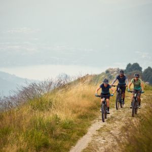 Three friends riding Liv Tempt E+ mountain bikes over a hill.
