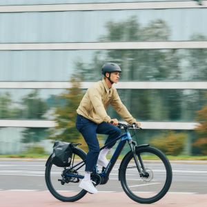 A commuting cyclist pedals by on a city street on their Giant Talon E+ EX hardtail bike.