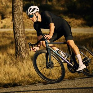 A road cyclist descends through a mountain corner on a custom titanium road bike with CADEX Aero Tires.