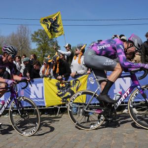 Two Jayco Alula pro cyclists ride over cobbles on Giant road bikes with CADEX Aero Cotton Tires.