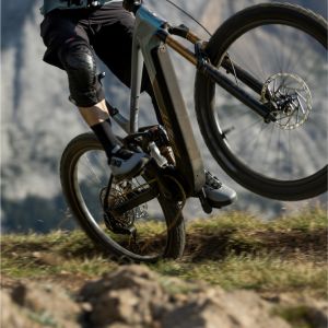 A mountain biker on a Giant Trance Advanced E+ trail bike with Contact SLR Trail Integrated Handlebar hits a small jump on a singletrack trail.