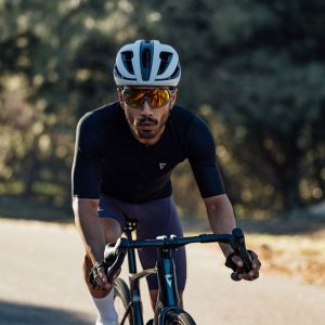 A cyclist approaches on a slight descent on a forest road wearing a Giant Rev Pro helmet.