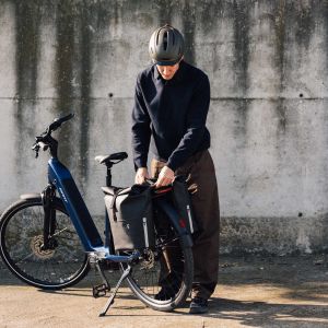 A rider adjusts something on the rear rack on their Giant NewTour E+ city bike.