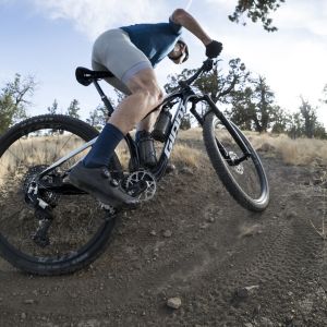 A mountain biker on a Giant Anthem Advanced SL with a Giant Contact Switch dropper post rides through a forested trail.